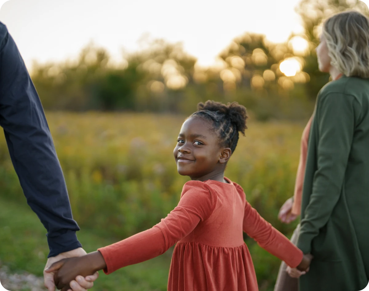 Child smiling and holding hands outdoors